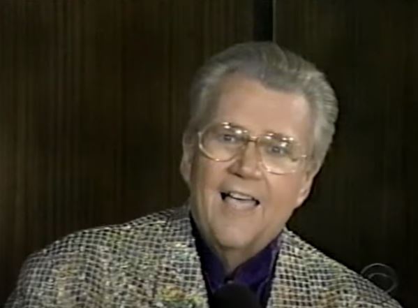 Rod is wearing a gold sequined jacket & purple silk collarless shirt