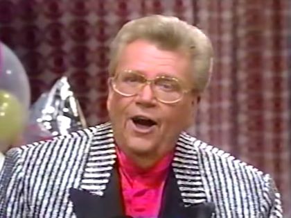 Rod is wearing a shiny black & white-striped jacket with black lapels & fuchsia collarless silk shirt