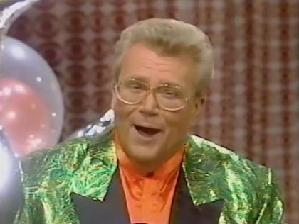 Rod is wearing a shiny green jacket with black lapels & salmon collarless silk shirt