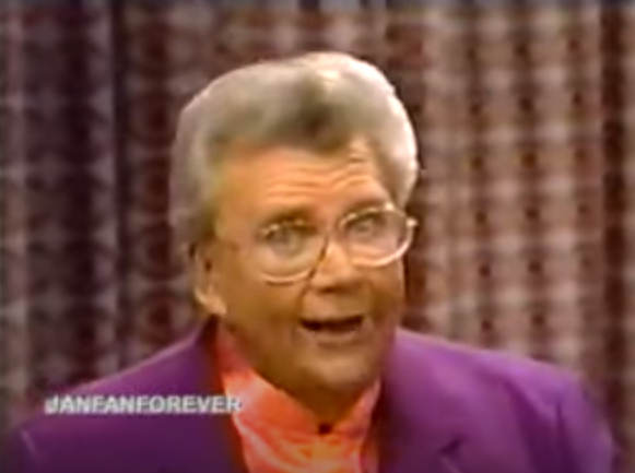 Rod is wearing a purple jacket & salmon-colored silk collarless shirt
