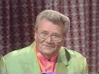 Rod is wearing an avocado green jacket & salmon collarless silk shirt