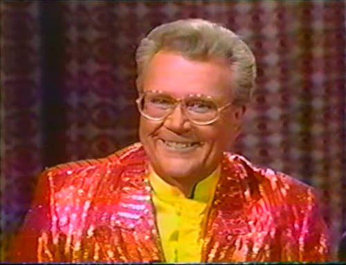 Rod is wearing a shiny red/red-striped jacket & yellow collarless silk shirt