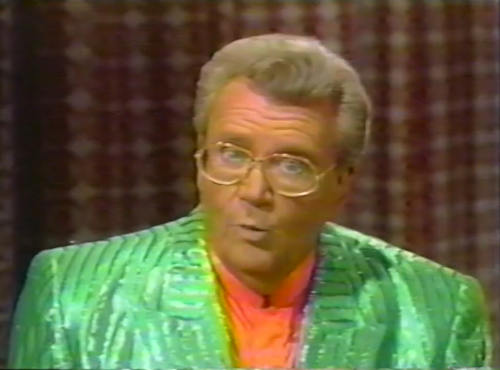 Rod is wearing a shiny green/green-striped acket & peach collarless silk shirt