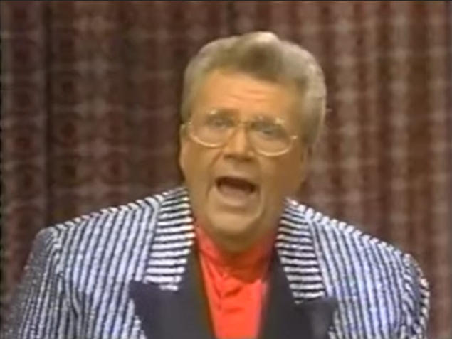 Rod is wearing a shiny black and white-striped jacket with black lapels 
 & red collarless silk shirt
