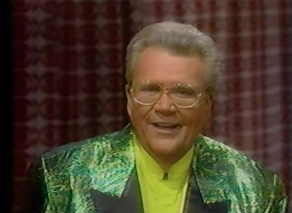 Rod is wearing a shiny green jacket with black lapels & yellow collarless silk shirt