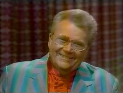 Rod is wearing a green/gray striped jacket & red collarless silk shirt