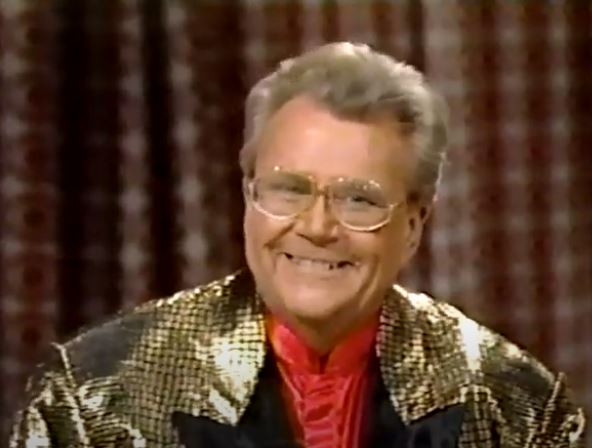 Rod is wearing a gold sequined jacket with black lapels & red silk collarless shirt