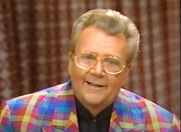Rod is wearing a rainbow plaid jacket & black collarless silk shirt