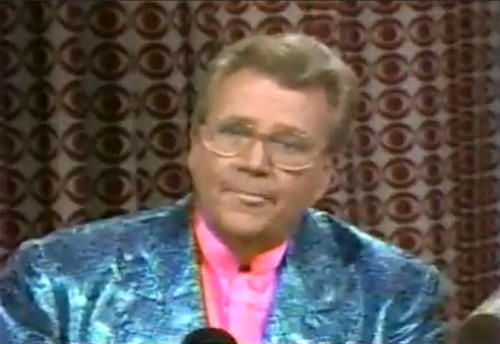 Rod is wearing a bluish-grey sequined jacket & pink collarless silk shirt