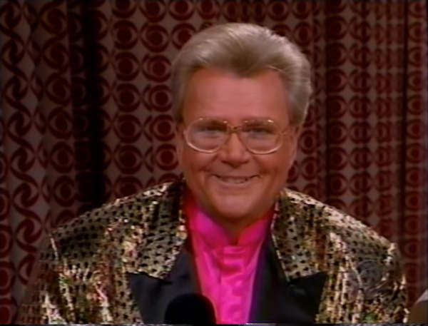 Rod is wearing a shiny leopard-print jacket with black lapels & fuchsia collarless silk shirt