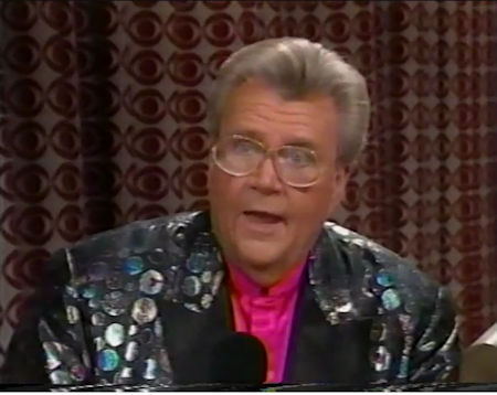 Rod is wearing a black jacket with silver spots, black lapels & fuchsia collarless silk shirt