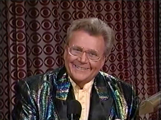 Rod is wearing a sequined 'oil-slick' jacket with black lapels & cream-colored collarless silk shirt