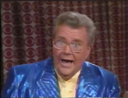 Rod is wearing a shiny blue/blue-striped jacket & yellow collarless silk shirt