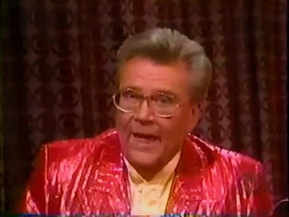 Rod is wearing a shiny red/red-striped jacket & yellow collarless silk shirt