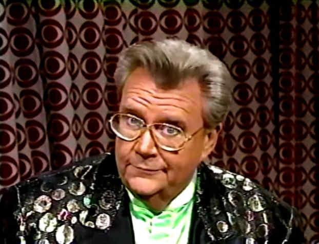 Rod is wearing a black jacket with silver spots, black lapels & a lime-green collarless silk shirt