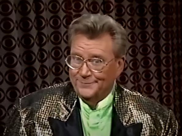 Rod is wearing a black & gold sequined jacket with black lapels & lime-green silk collarless shirt
