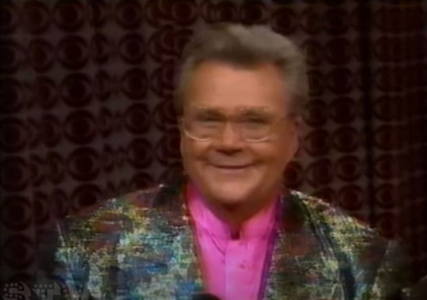 Rod is wearing a shiny multi-colored jacket & pink collarless silk shirt