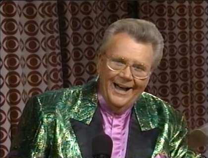 Rod is wearing a shiny green jacket with black lapels & lavender collarless silk shirt