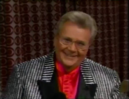 Rod is wearing a shiny black & white-striped jacket with black lapels & red collarless silk shirt