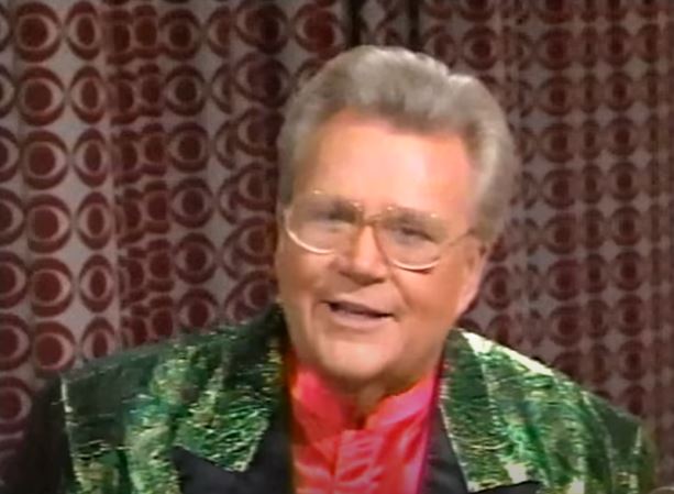 Rod is wearing a shiny green/gold jacket with black lapels & red collarless silk shirt