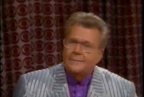 Rod is wearing a silver/grey-striped jacket & purple collarless silk shirt