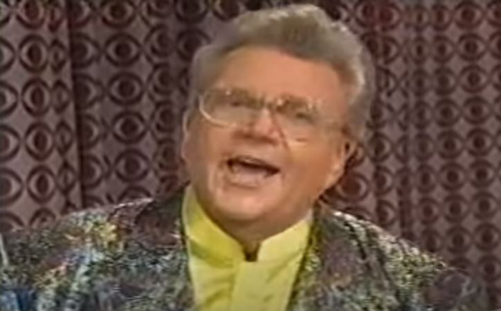 Rod is wearing an iridescent silver jacket & yellow silk collarless shirt