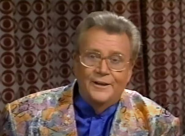 Rod is wearing a multi-pastel-patterned jacket & blue collarless silk shirt