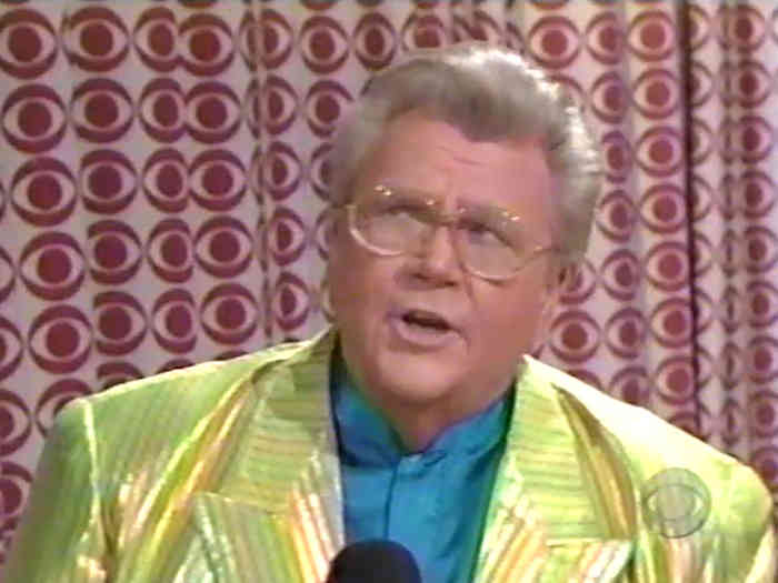 Rod is wearing a shiny yellow-green jacket with darker stripes & teal-blue collarless silk shirt