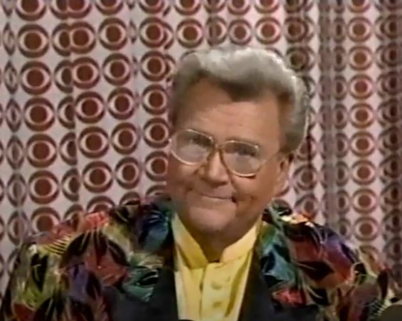 Rod is wearing a multi-colored feather-patterned jacket & yellow silk collarless shirt