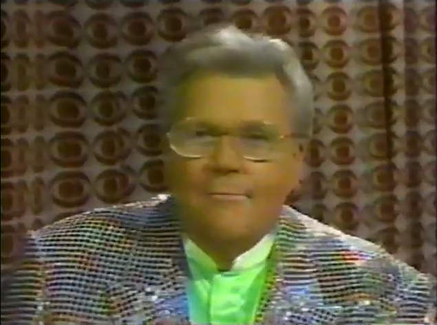 Rod is wearing a white jacket with black sequins & a lime green collarless silk shirt