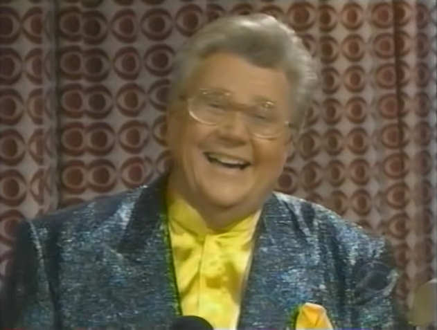 Rod is wearing a shiny dark-green jacket & yellow collarless silk shirt with matching pocket square