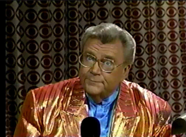 Rod is wearing a shiny orange/orange-striped jacket & light blue collarless silk shirt