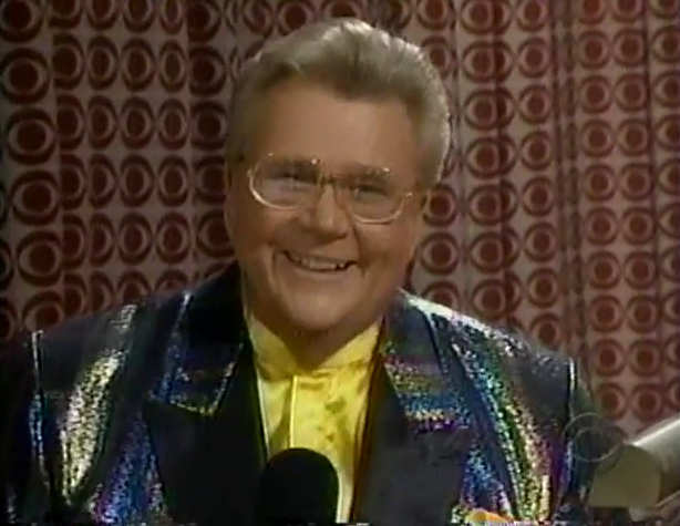 Rod is wearing an 'oil-slick' sequined jacket with black lapels, yellow collarless silk shirt & matching pocket square