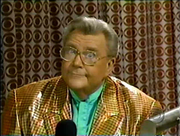 Rod is wearing a shiny orange gingham jacket & green collarless silk shirt