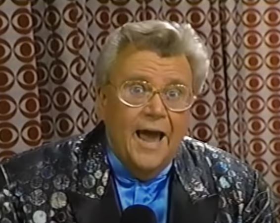 Rod is wearing a black jacket w/ irridescent circles & blue collarless silk shirt