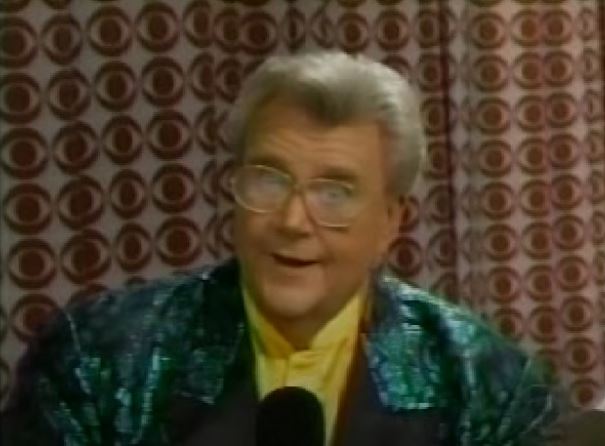 Rod is wearing a shiny green jacket with black lapels & yellow collarless silk shirt