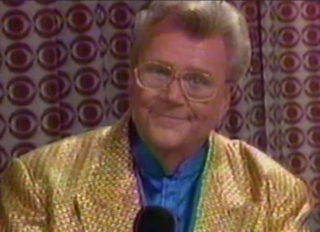 Rod is wearing a shiny gold jacket & blue collarless silk shirt