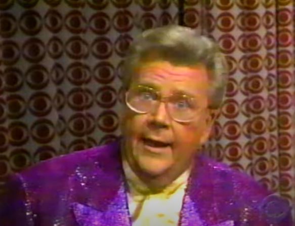 Rod is wearing a purple sequined jacket & yellow collarless silk shirt