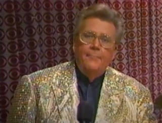 Rod is wearing a gold sequined jacket & black collarless silk shirt