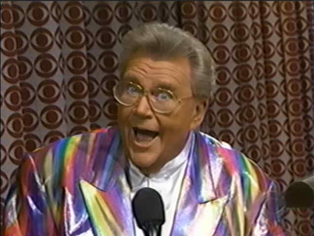 Rod is wearing a shiny red-yellow-blue-purple striped jacket & white collarless silk shirt