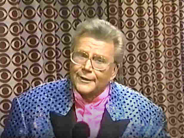 Rod is wearing a blue sequined jacket with black spots, black lapels & a pink collarless silk shirt