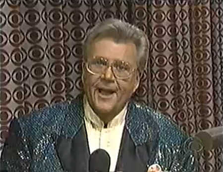 Rod is wearing a dark-green sequined jacket with black lapels & a pastel-yellow collarless silk shirt with matching pocket square