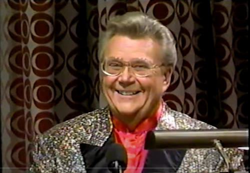 Rod is wearing a gold sequined jacket with balck lapels & salmon collarless silk shirt