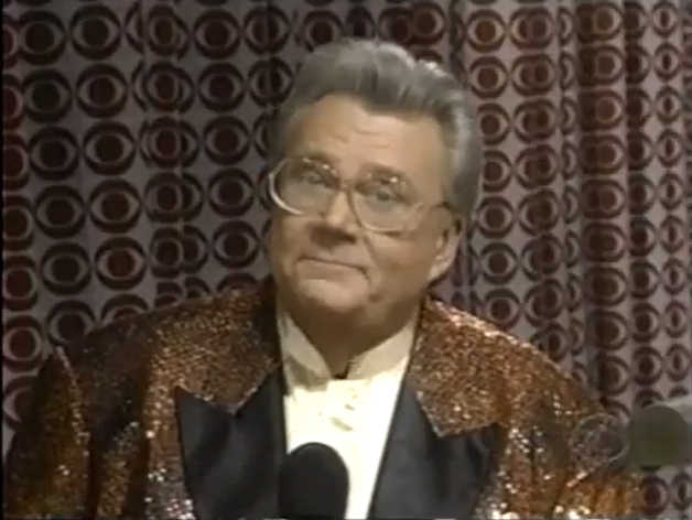 Rod is wearing a brown sequined jacket with black lapels & white collarless silk shirt