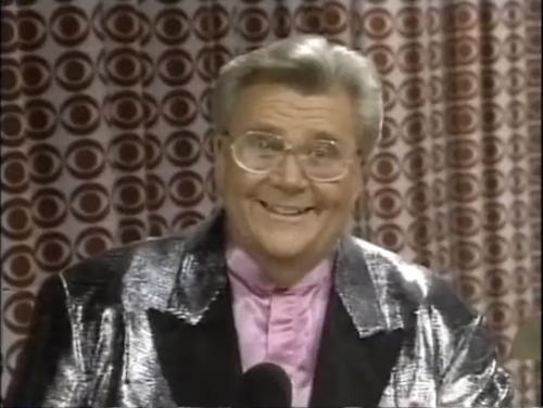 Rod is wearing a silver jacket with black lapels & light-pink collarless silk shirt
