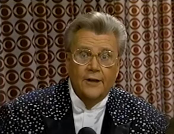 Rod is wearing a black jacket with white speckles & white collarless silk shirt
