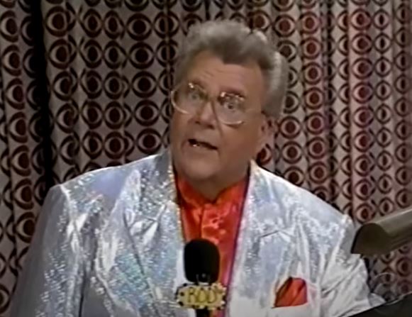 Rod is wearing a silver sequined jacket & red silk collarless shirt