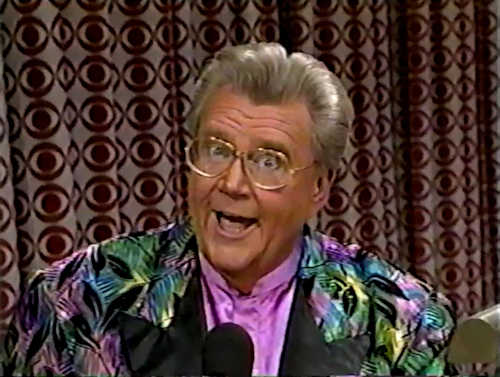 Rod is wearing a multi-colored feather-patterned jacket with black lapels & lavender collarless silk shirt