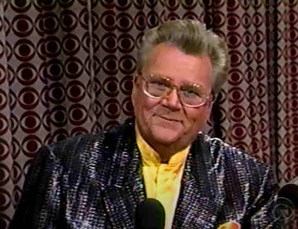 Rod is wearing a black sequined jacket, yellow silk pocket square & yellow silk collarless shirt