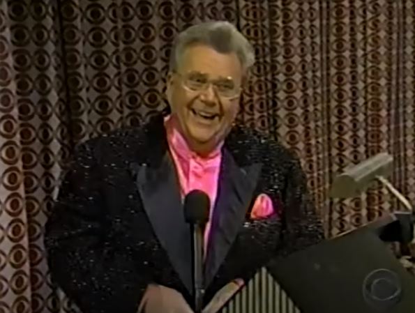 Rod is wearing a black sequined jacket & pink collarless silk shirt with matching pocket square